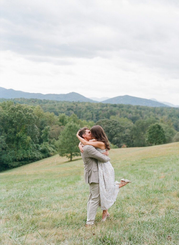 Couple kissing in field with mountains in the background