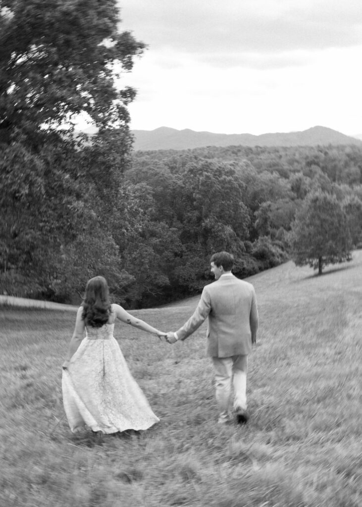 Black and white of a couple holding hands walking in field