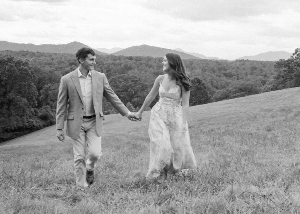 Black and White of couple walking through field holding hands