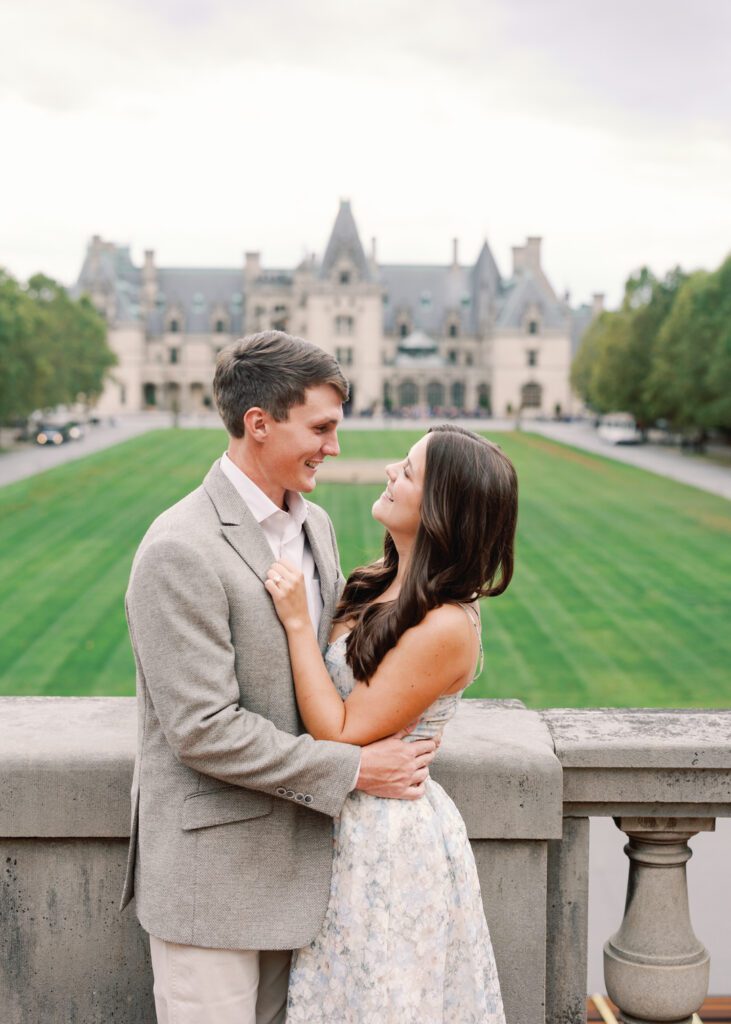 Couple smiling at each other with the Biltmore Estate in background