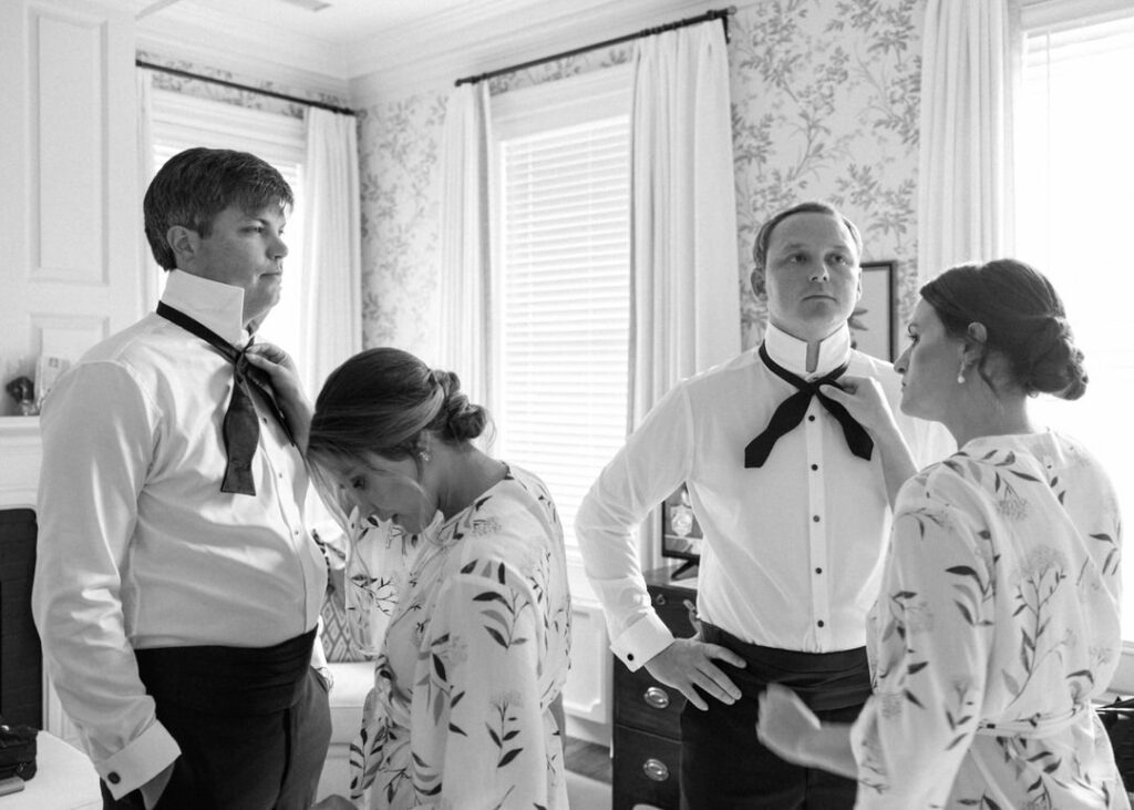 black and white of groom and best man getting ready 