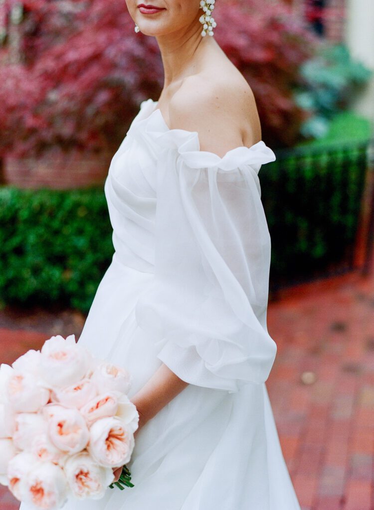 Detail of brides sleeve holding bouquet