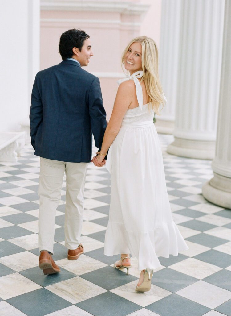 couple walking holding hands bride looking over her shoulder