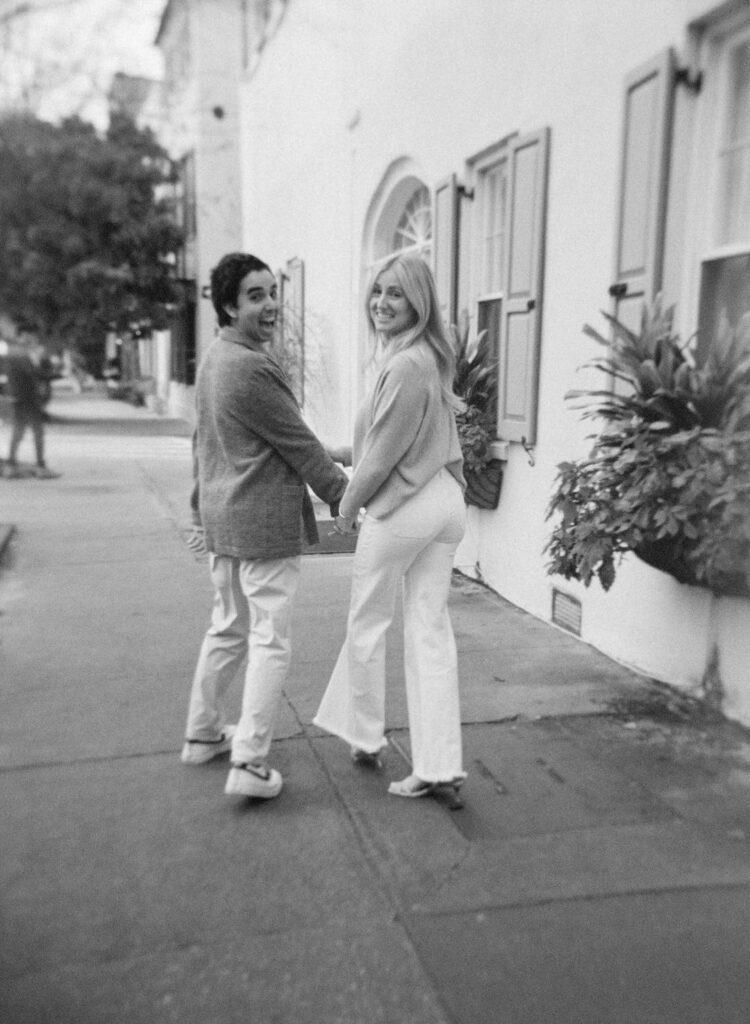 black and white of a couple looking behind them walking and smiling