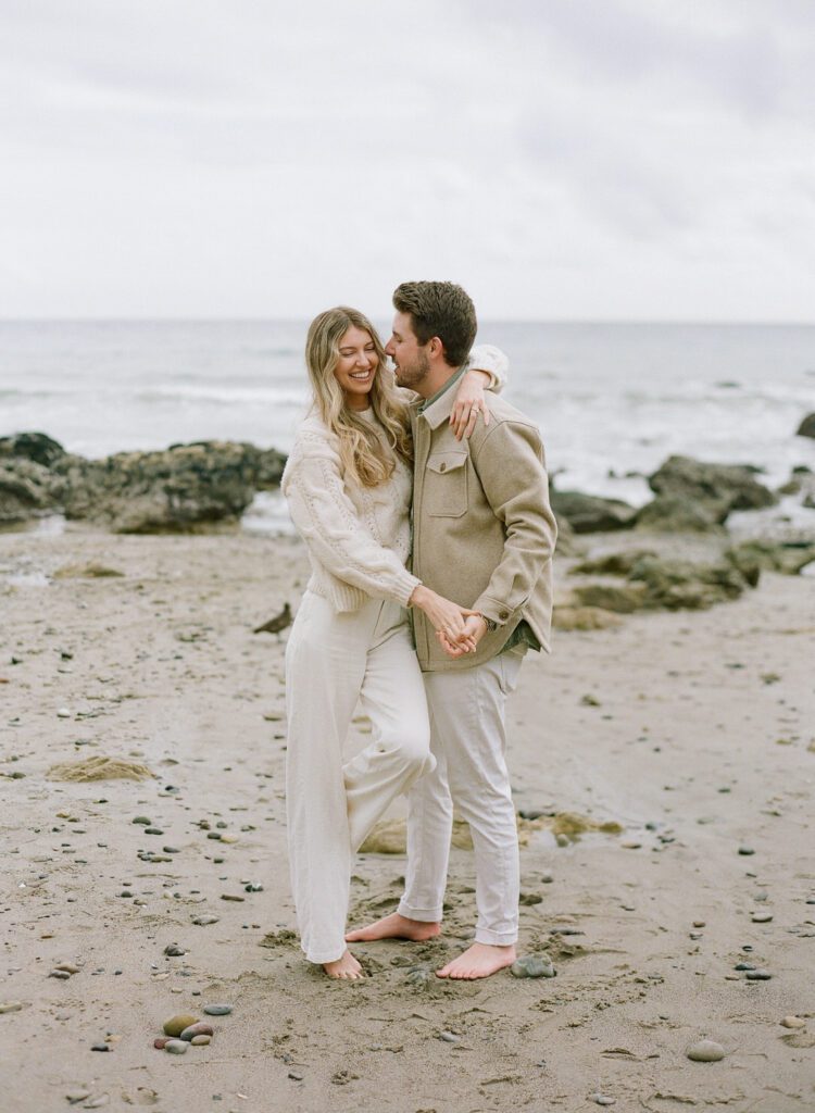 couple holding hands hugging on the beach