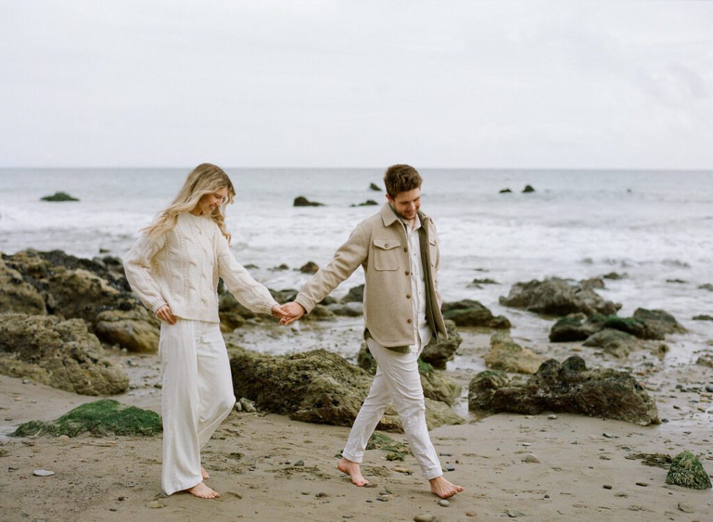 couple holding hands walking on beach