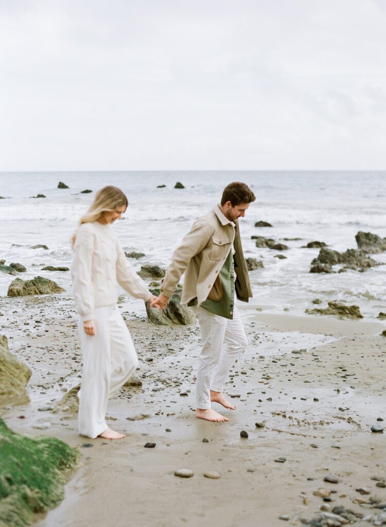 couple holding hands walking on the beach