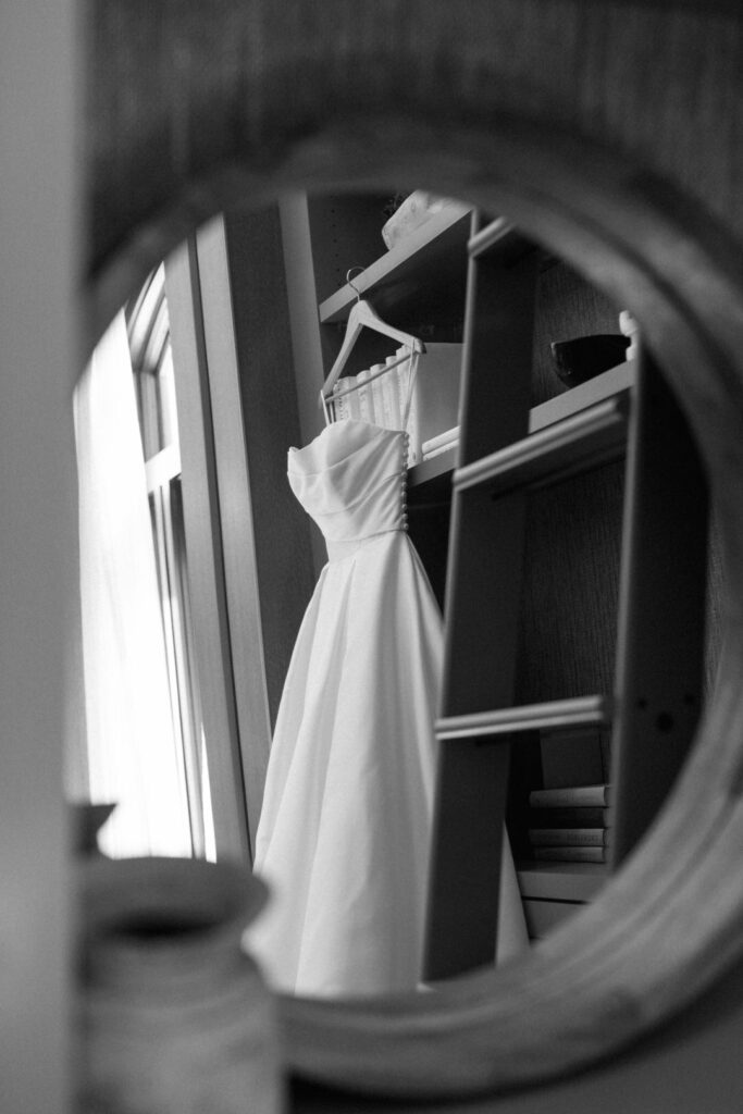 black and white of brides wedding dress hanging 