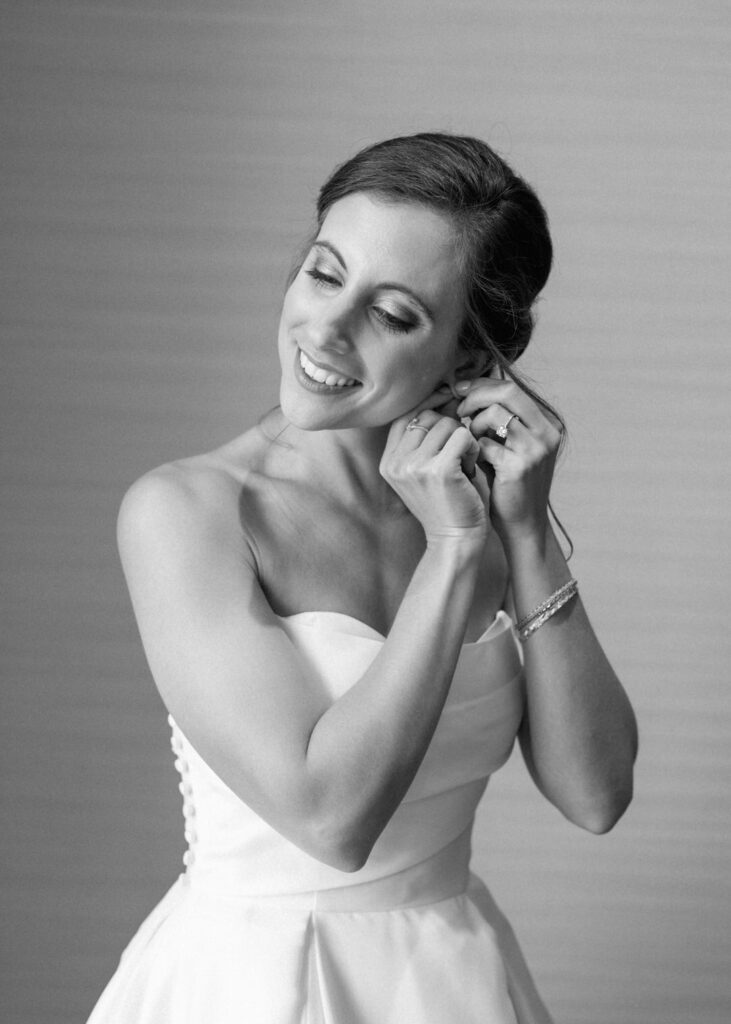 black and white of bride putting in earrings 