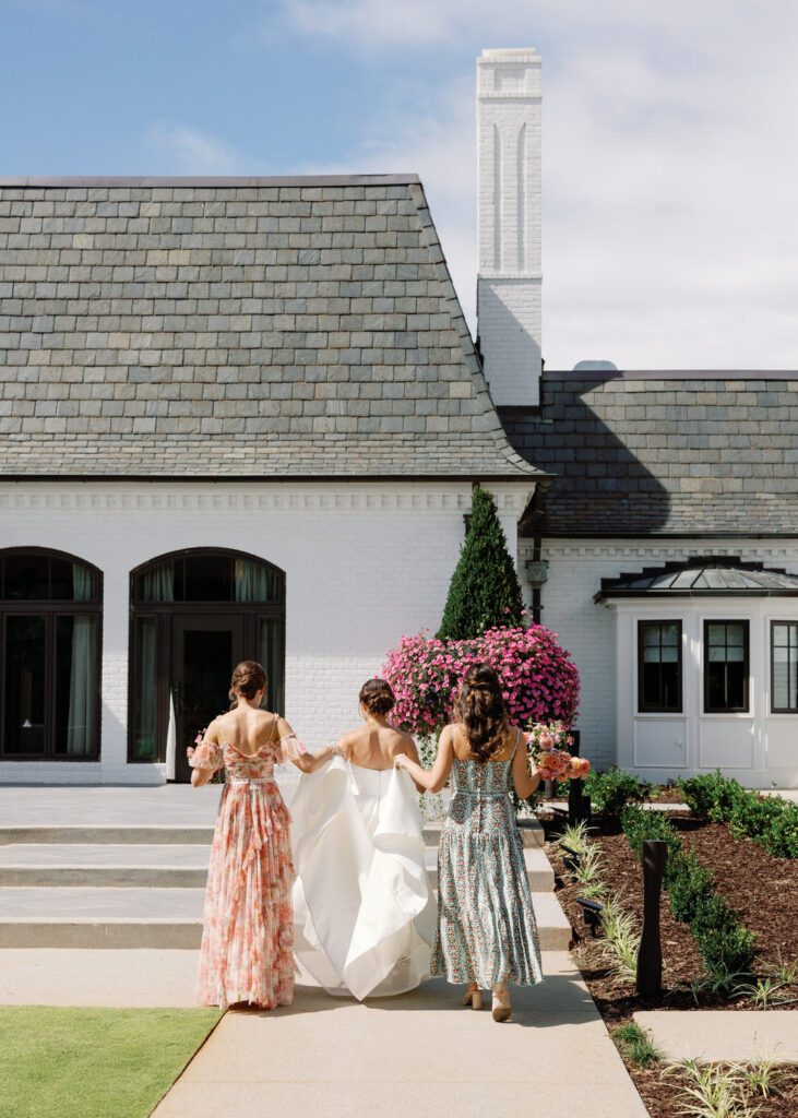 bride walking with bridesmaids holding her train 