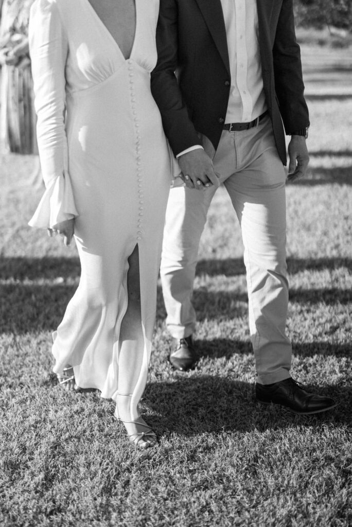 black and white of bride and groom holding hands