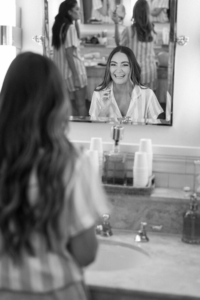 black and white of bridesmaid laughing in mirror