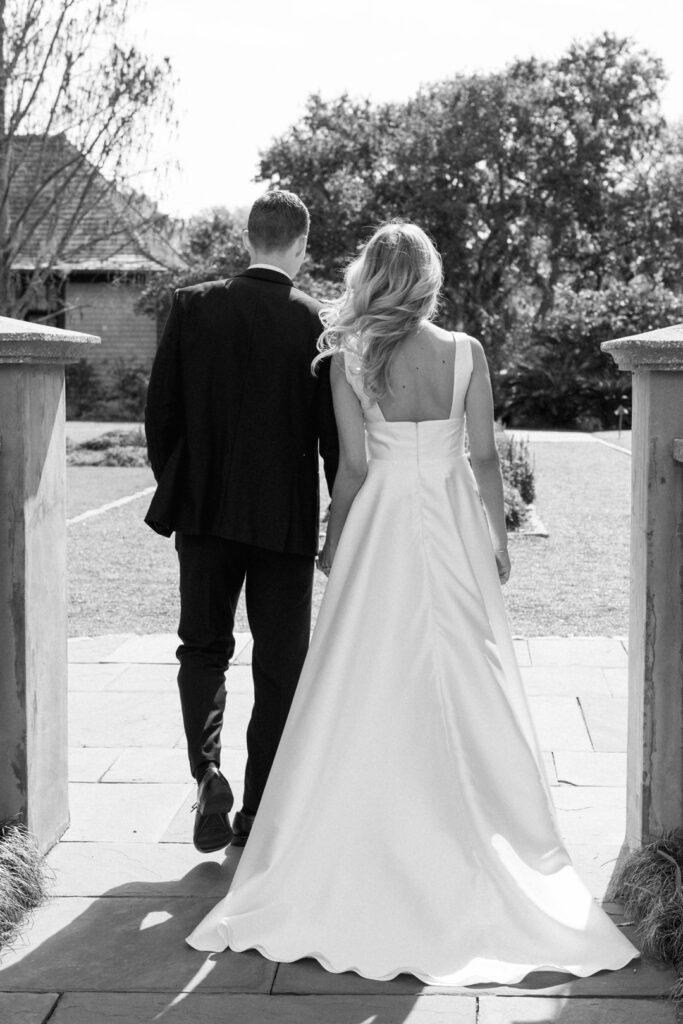 black and white of bride and groom holding hands walking