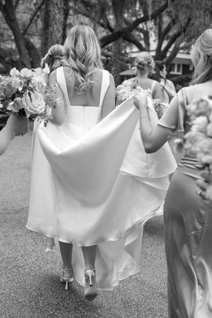 black and white of bridesmaids carrying brides train