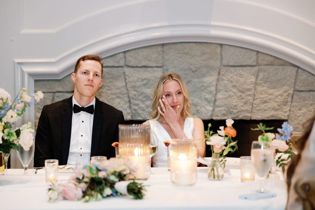 Crying bride and groom listening to speeches at wedding reception