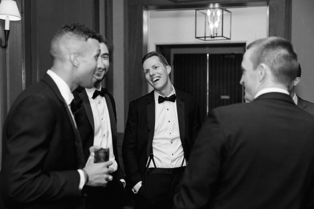 black and white of groom laughing with friends