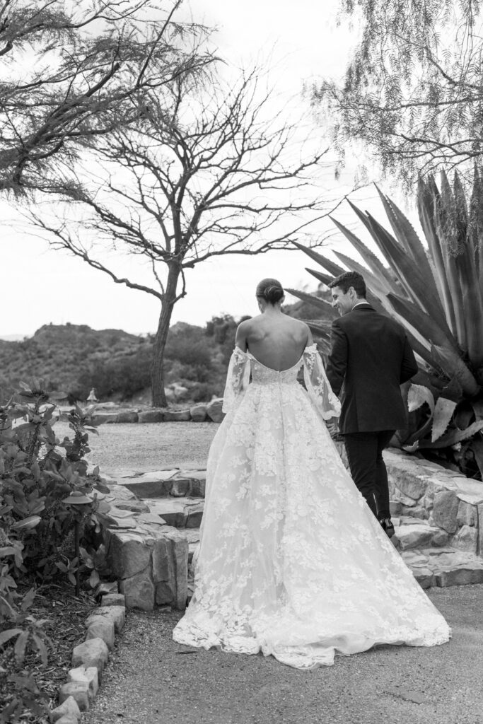 Black and white of bride and groom holding hands 