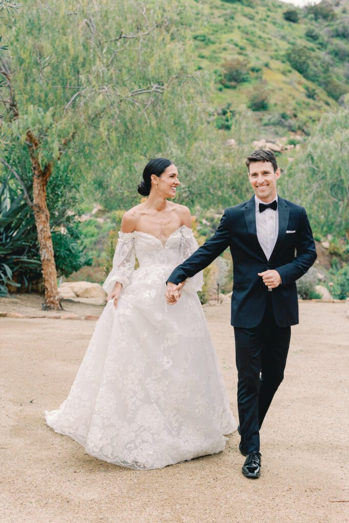 Bride and Groom holding hands walking and laughing.