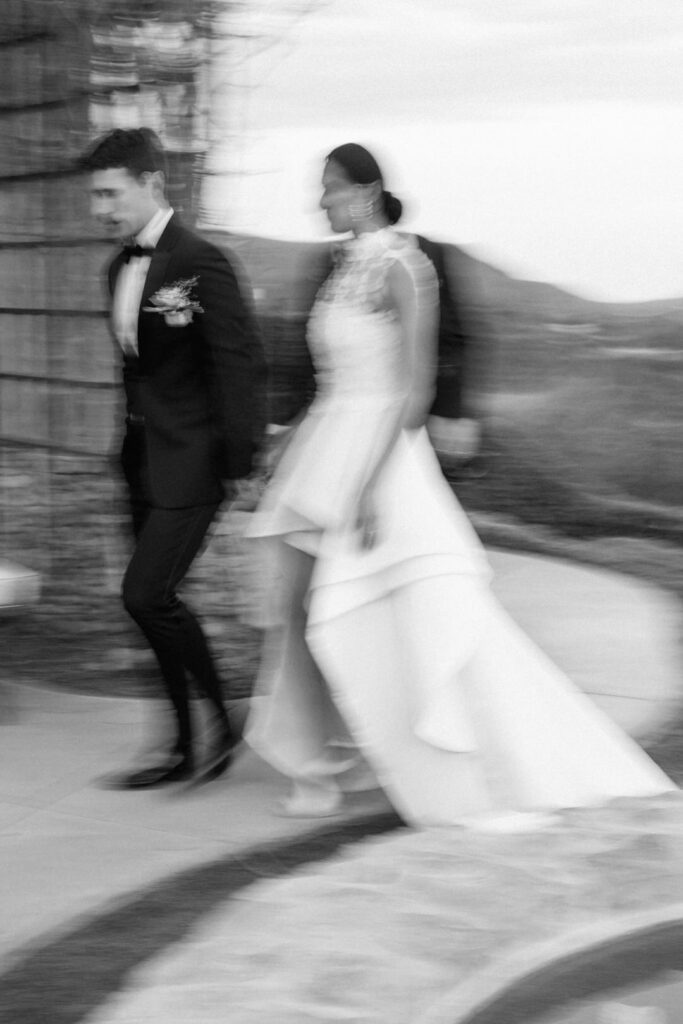 black and white of bride and groom Walking by pool 