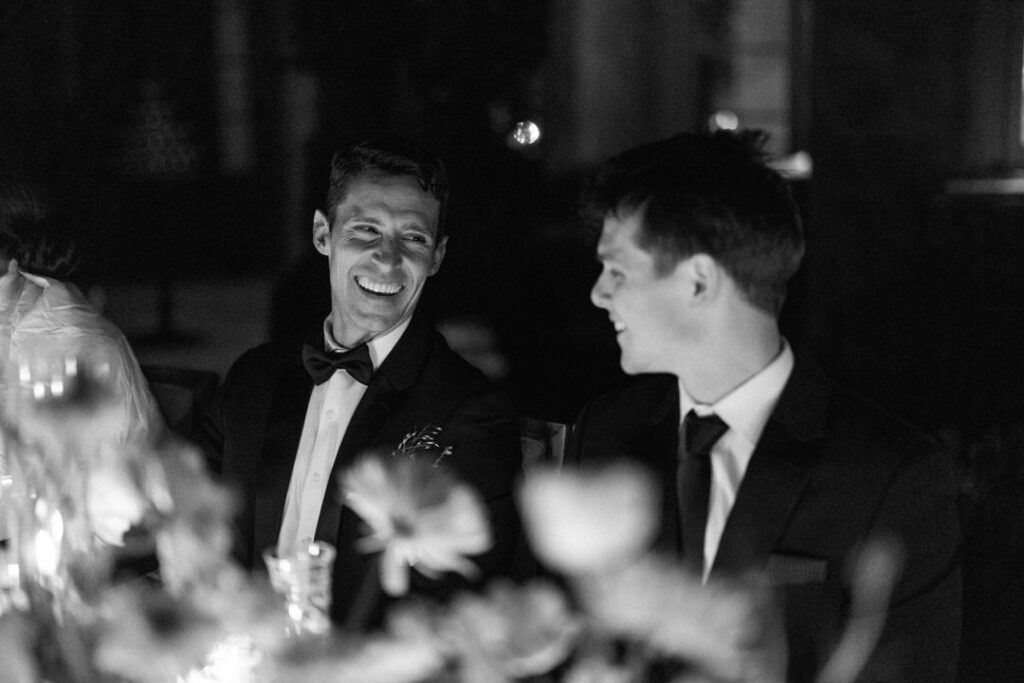 black and white of groom and best man laughing 