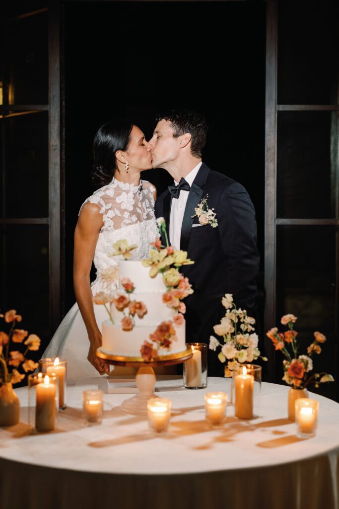 bride and groom kissing cutting cake 