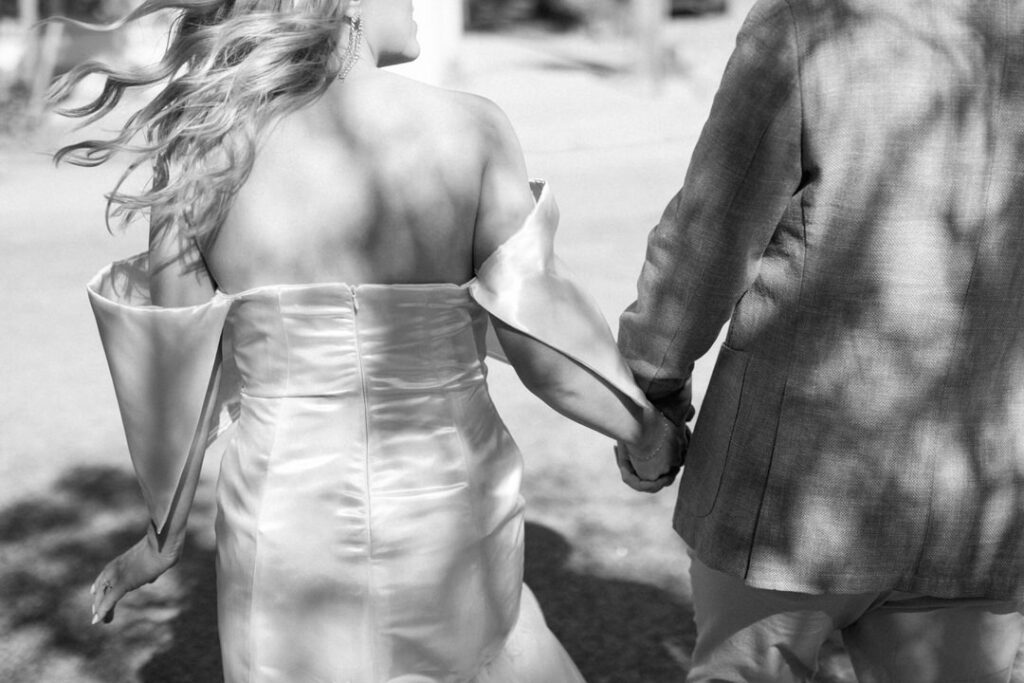 black and white of bride and groom holding hands