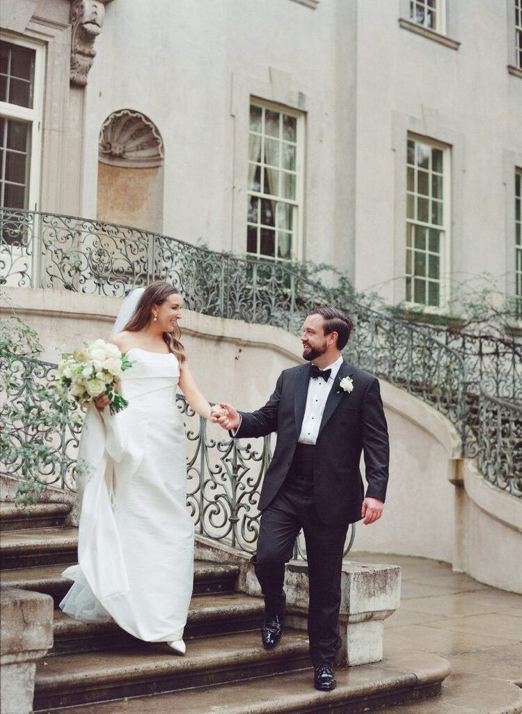 bride and groom holding hands walking down stairs at Swan House