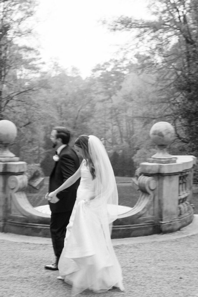 black and white of bride and groom walking holding hands