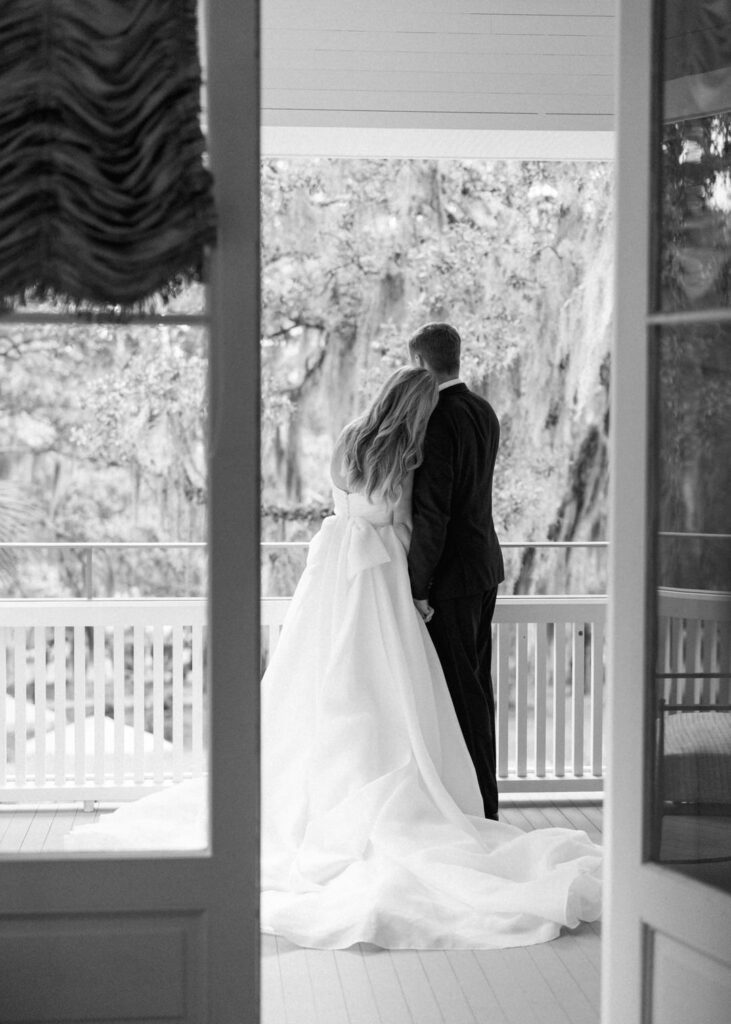 black and white of bride and groom on the porch of The Admiral's House