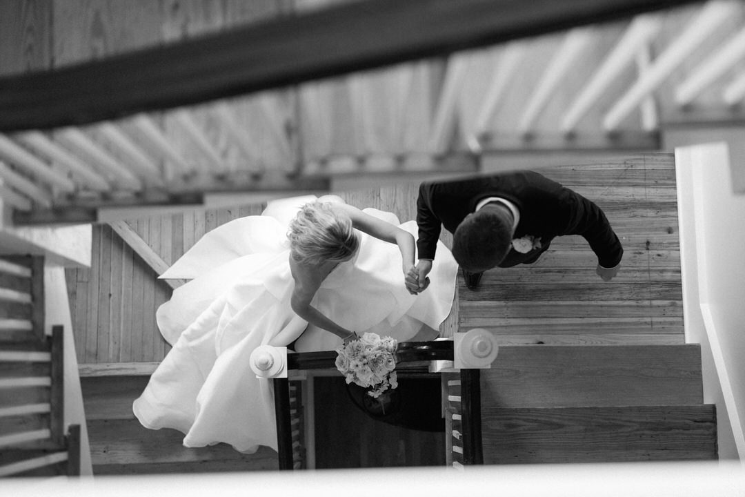 black and white of bride and groom walking up stairs