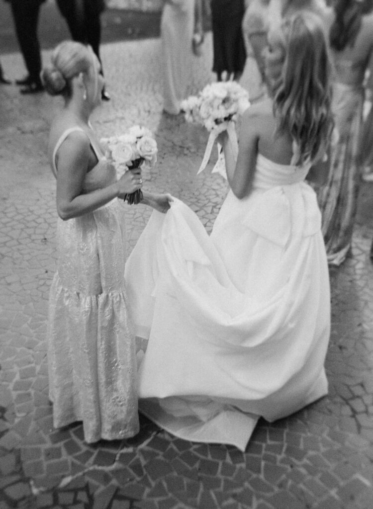 black and white of bride's sister holding dress