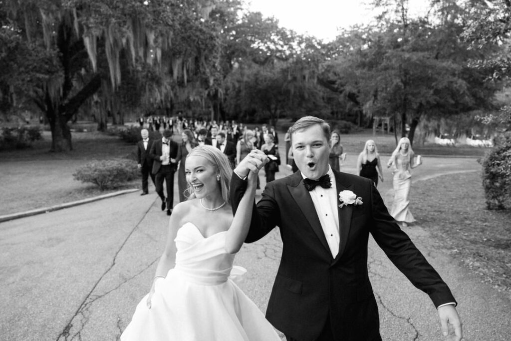 black and white of bride and groom leading guests to dinner