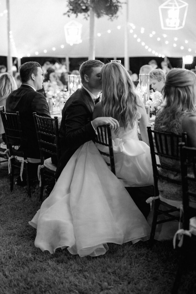 black and white of bride and groom kissing at wedding reception