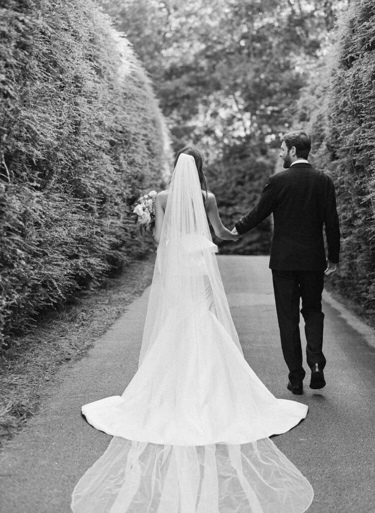 black and white of bride and groom holding hands