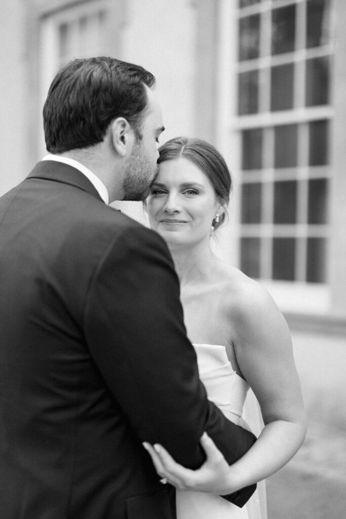 black and white of groom kissing bride