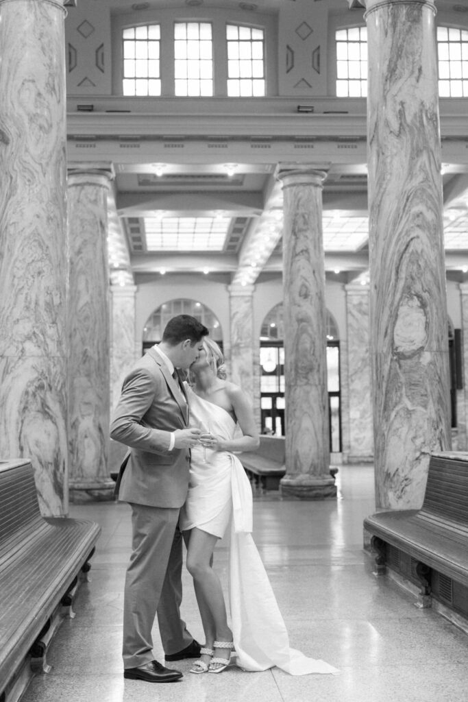 black and white bride and groom kissing in train station