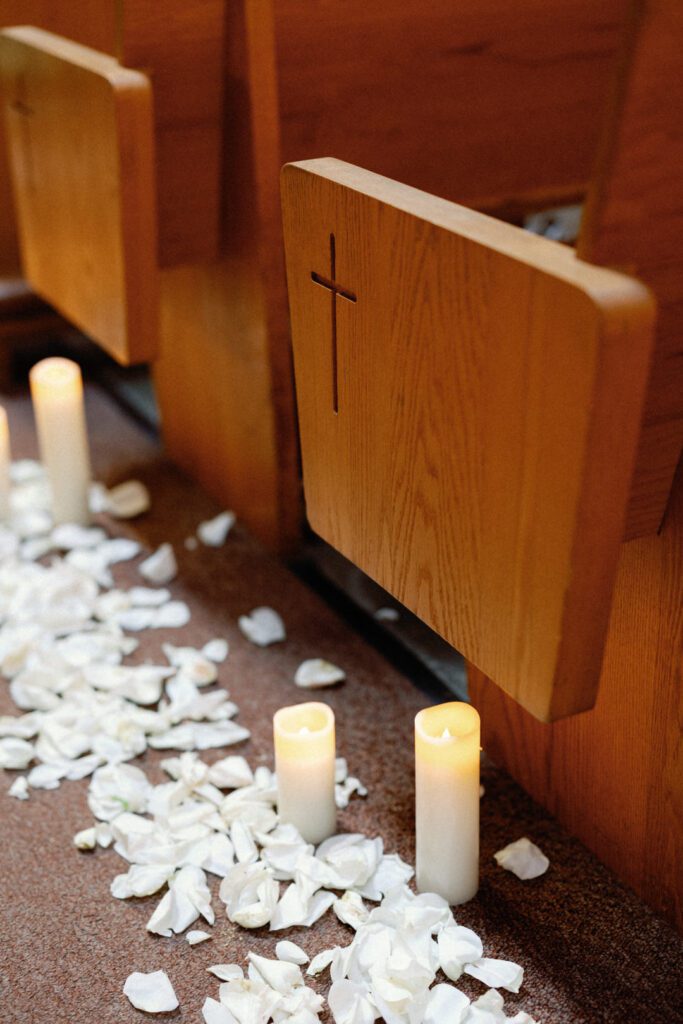 candles and flower petals on church floor with pews