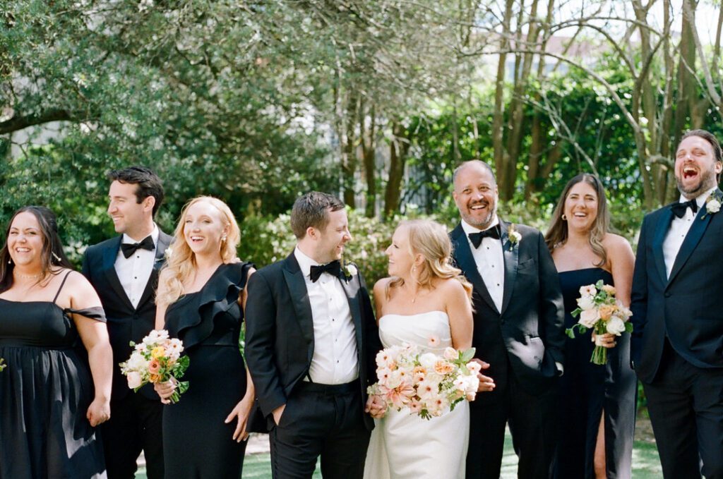 bride and groom laughing with wedding party