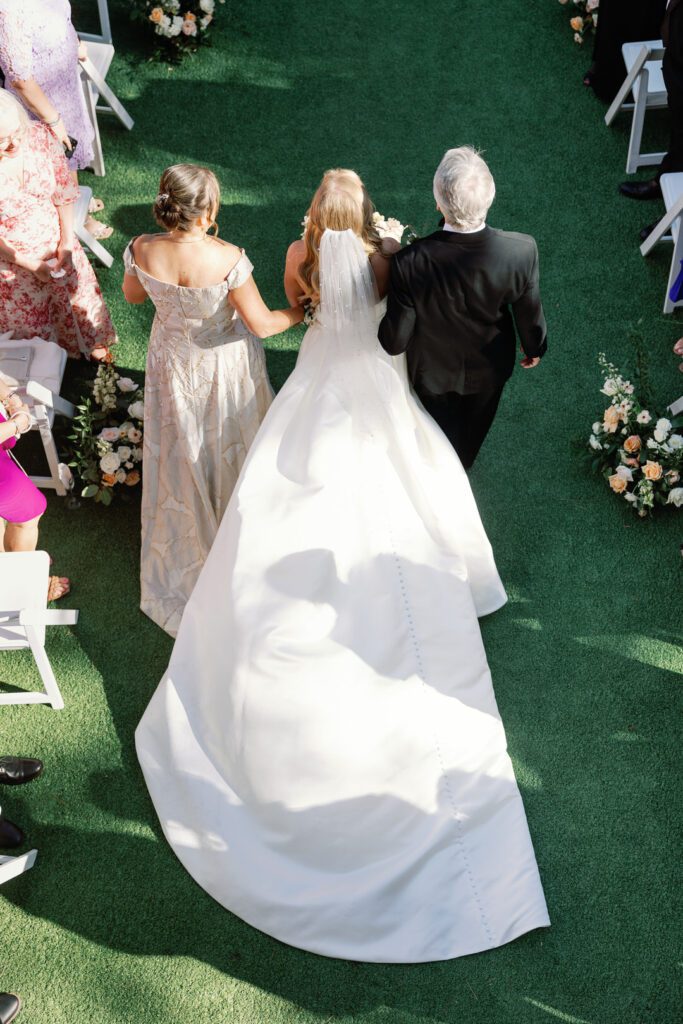 bride walking down aisle with mom and dad