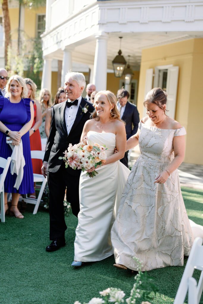 bride walking down aisle with mom and dad