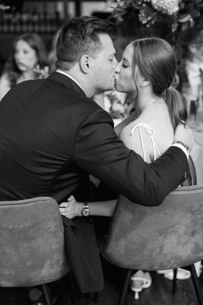 black and white of bride and groom kissing at rehearsal dinner