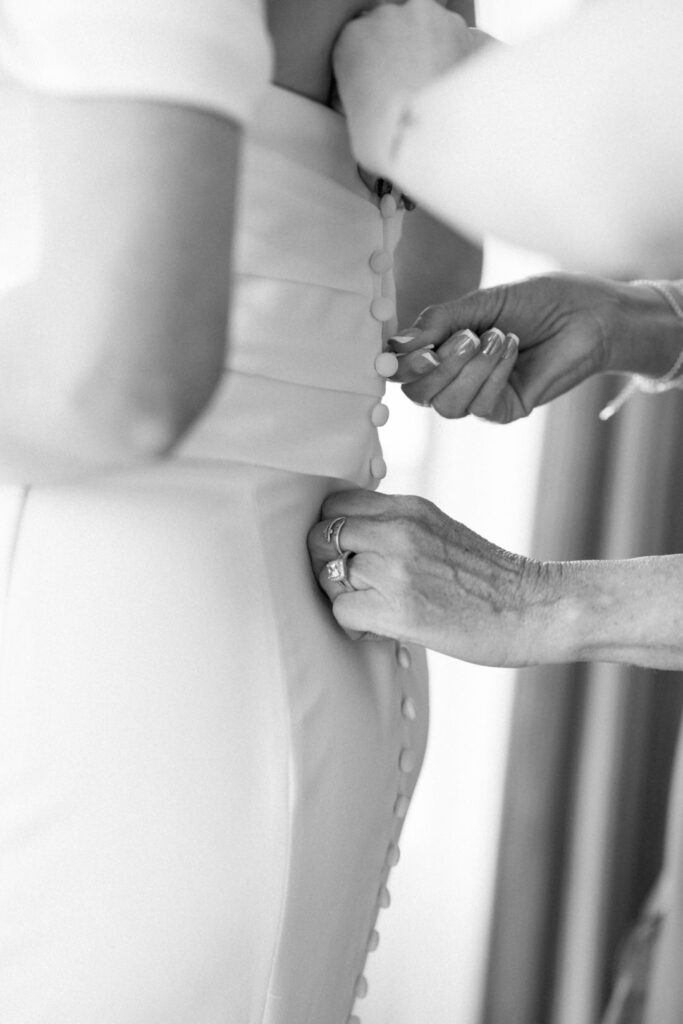 black and white of mom zipping brides dress