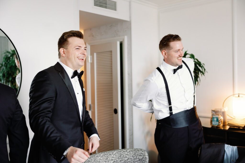 groom laughing with groomsmen getting dressed