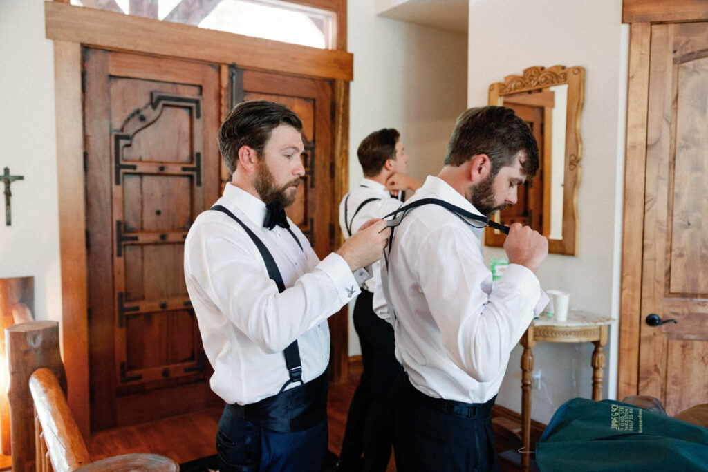 groom helping groomsmen get dressed