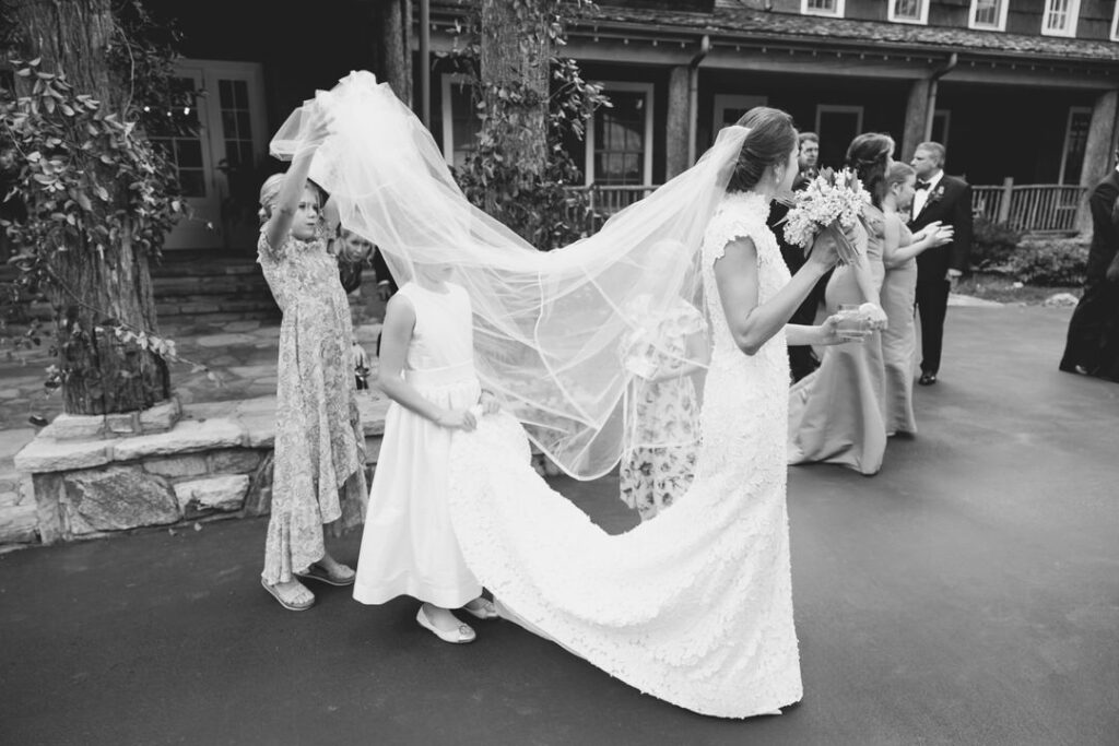 black and white of little girls holding up brides dress