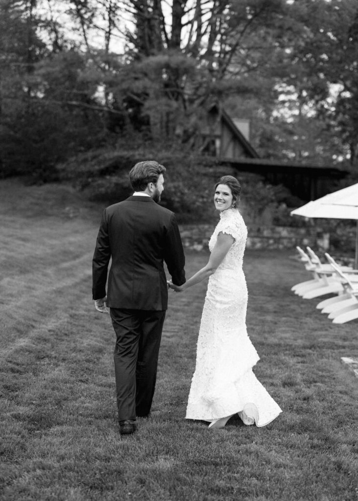 black and white of bride and groom walking holding hands