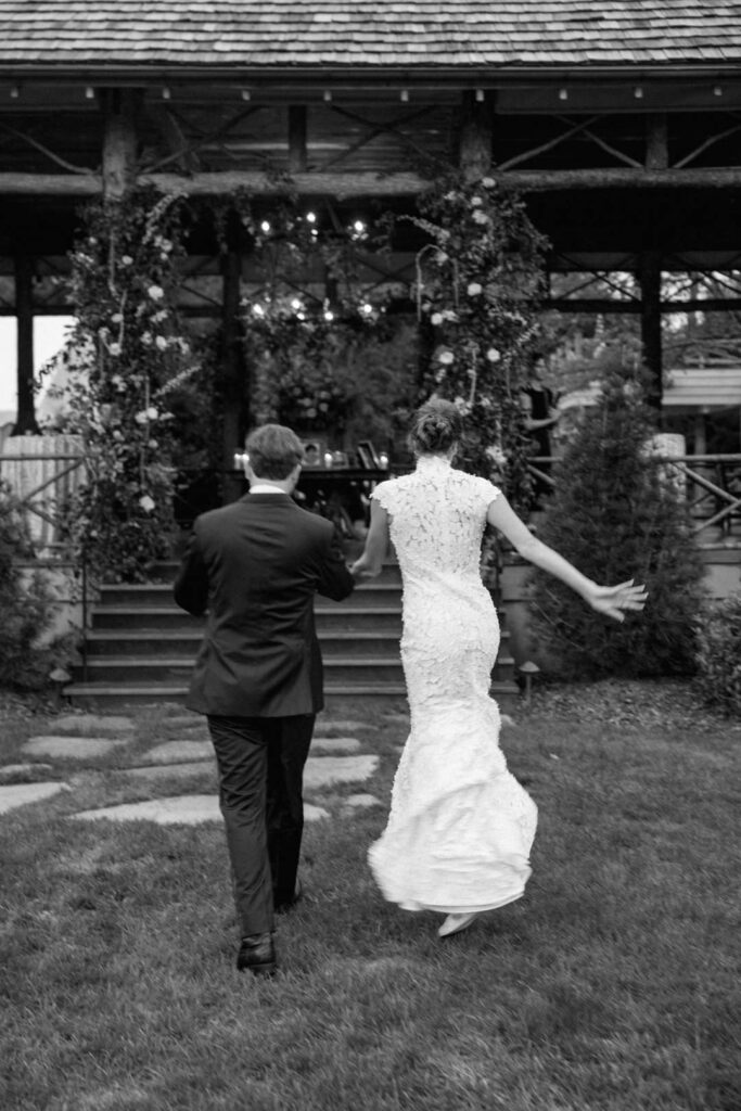 black and white of bride and groom walking away bride jumping