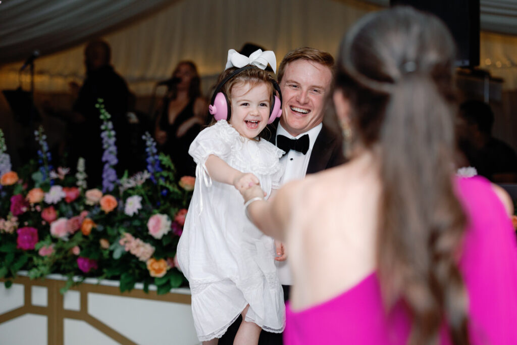 little girl with pink head phones on dancing with dad and mom