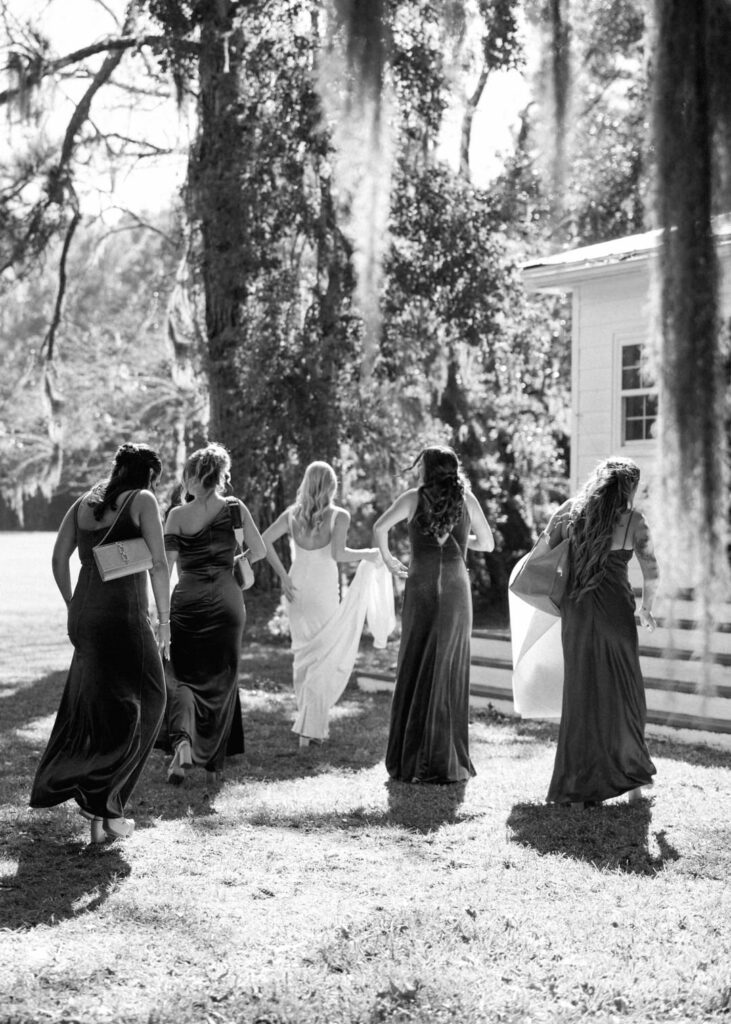 black and white of bride and bridesmaids walking into house