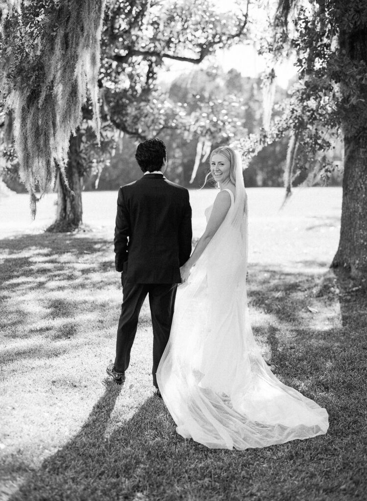 black and white of bride and groom holding hands walking